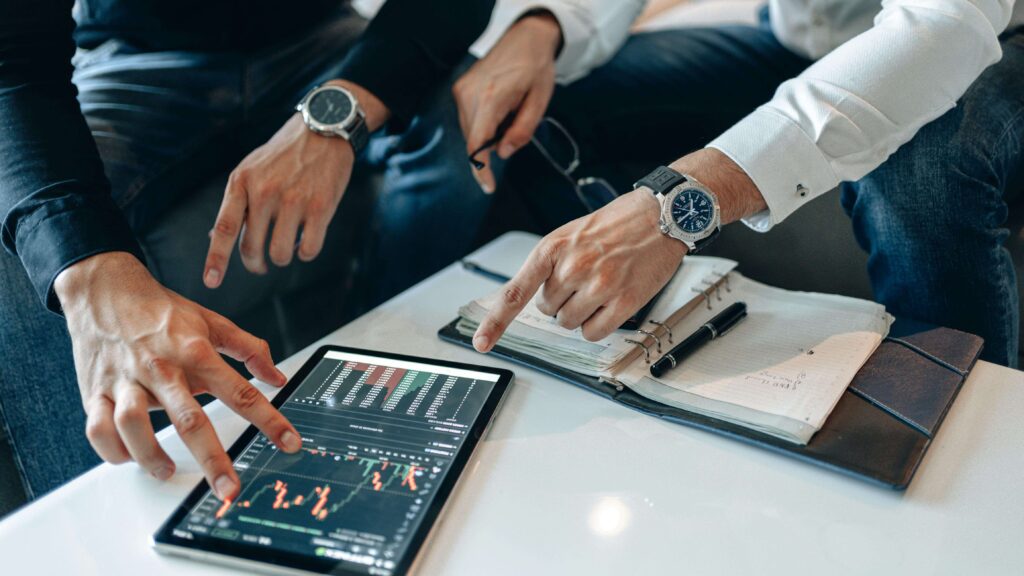 Two Men Analyze Finances on a Tablet.